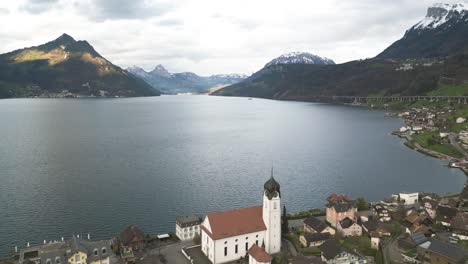 Aerial-View-of-Lake-Lucerne,-Beckenried-Village-Church-and-Swiss-Alps-Hills,-Drone-Shot