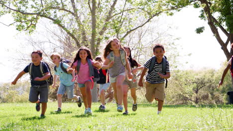 group of children with friends in park running towards camera shot in slow motion