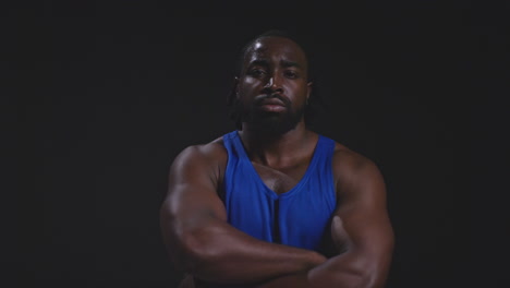 retrato de estudio de un atleta masculino con chaleco sudando después de un entrenamiento deportivo o haciendo ejercicio en el gimnasio doblando los brazos 4