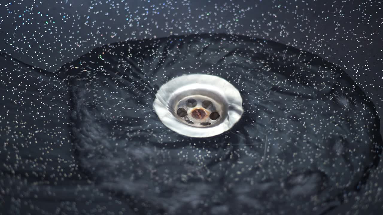 Eau tourbillonnant dans la bonde d'un évier sombre