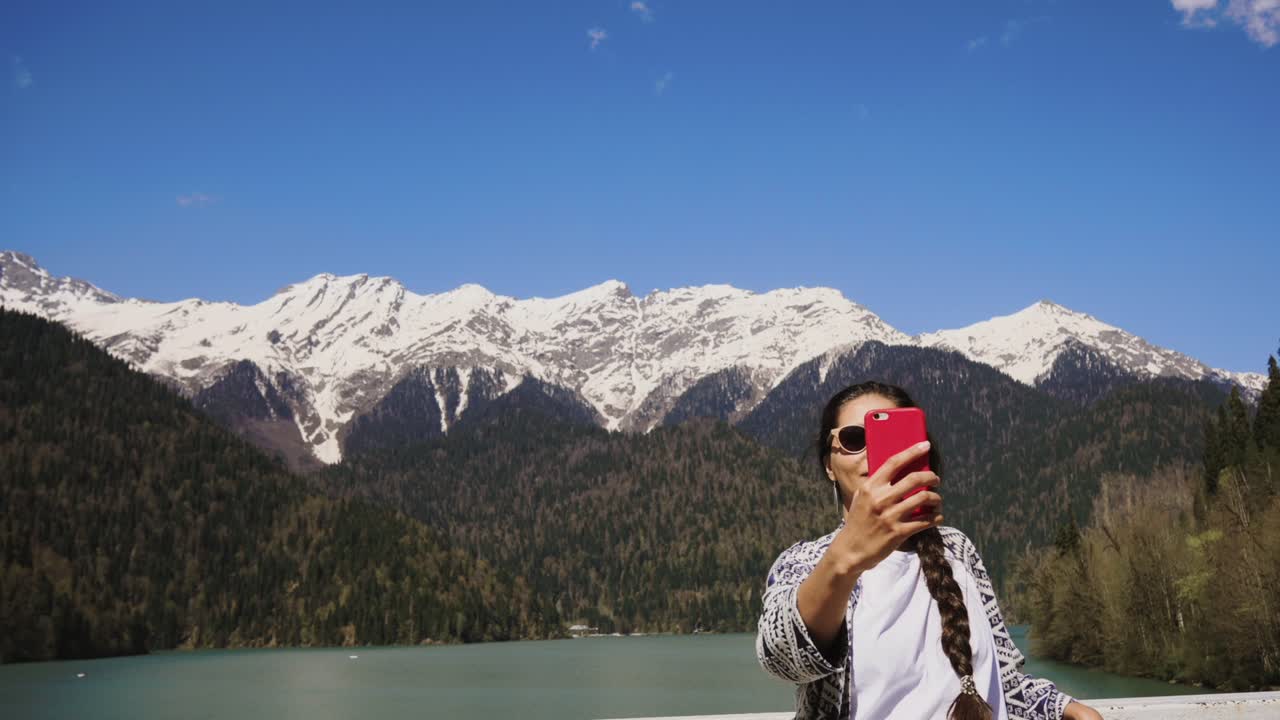 mujer tomando una selfie frente a un hermoso lago de montaña