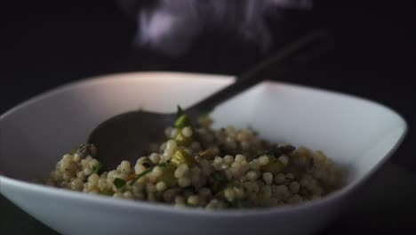 man leaving a spoon on a steamy plate of vegetarian couscous