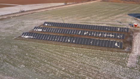 aerial drone view of a lightly snow covered solar panel station powering a farm