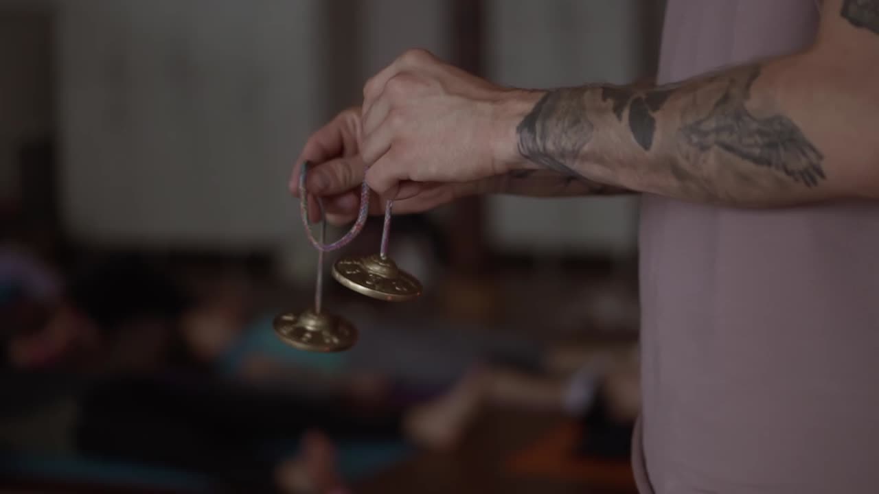 hombre tatuado irreconocible sostiene en sus manos un par de karatal de bronce en una cuerda, de cerca