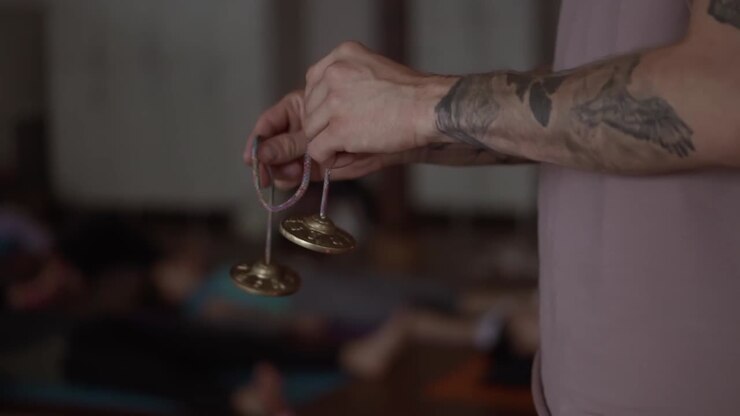 Unrecognizable tattoo man holdsin his hands a pair of bronze Karatal on a rope, close up