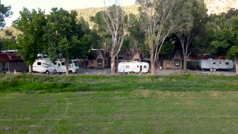 a wide panning drone shot of a small campground with rvs and tiny homes set in a large grass field in southern colorado