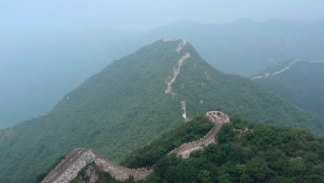 fly over rural part of great wall of china stretching over mountain ridge on a cloudy day