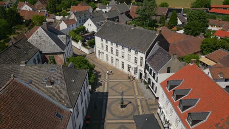 Aerial-drone-forward-shot-of-the-buildings-in-Wijngaard,-Thorn,-Maasgouw,-Limburg-with-view-of-the-historic-Dutch-community-with-pedestrians-on-the-street