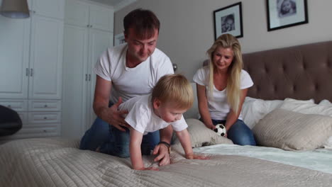 parents having fun with their little daughter on bed. family spending time at the morning