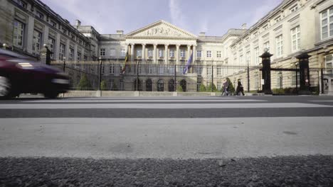 low wide angle shot from a crosswalk, pedestrians and traffic in front of belgian federal parliament building