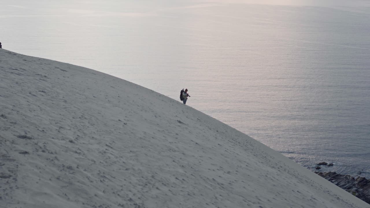 노르웨이의 일몰에 아름다운 바다와 해변을 바라보며 모래언덕에 서 있는 사람