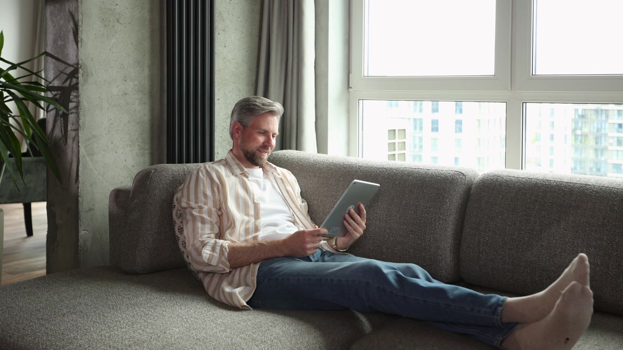 Relaxed Man Using Digital Tablet on Sofa in Modern Living Room