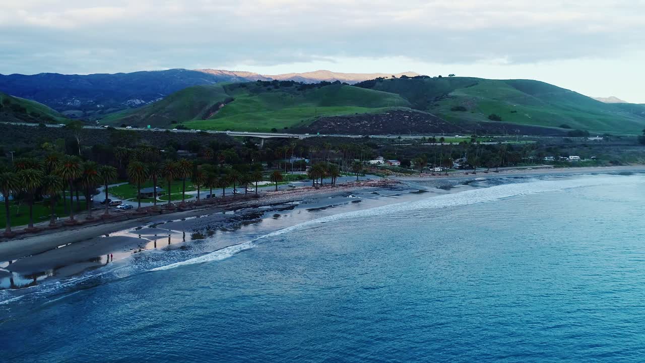Post-sunset drone shot of USA coastline drive with traffic lights and ocean glow in frame