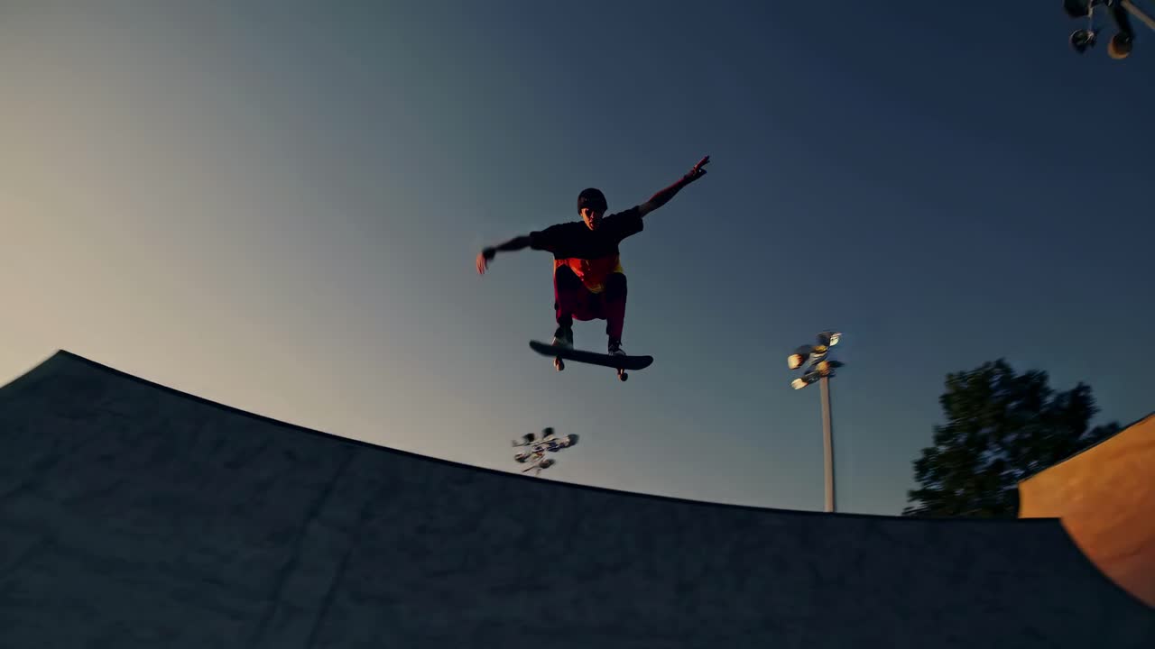 Silhouetted skateboarder mid-air at sunset, captured from a low-angle