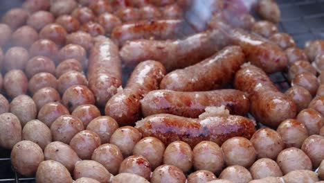 sausages being turned on a grill with potatoes