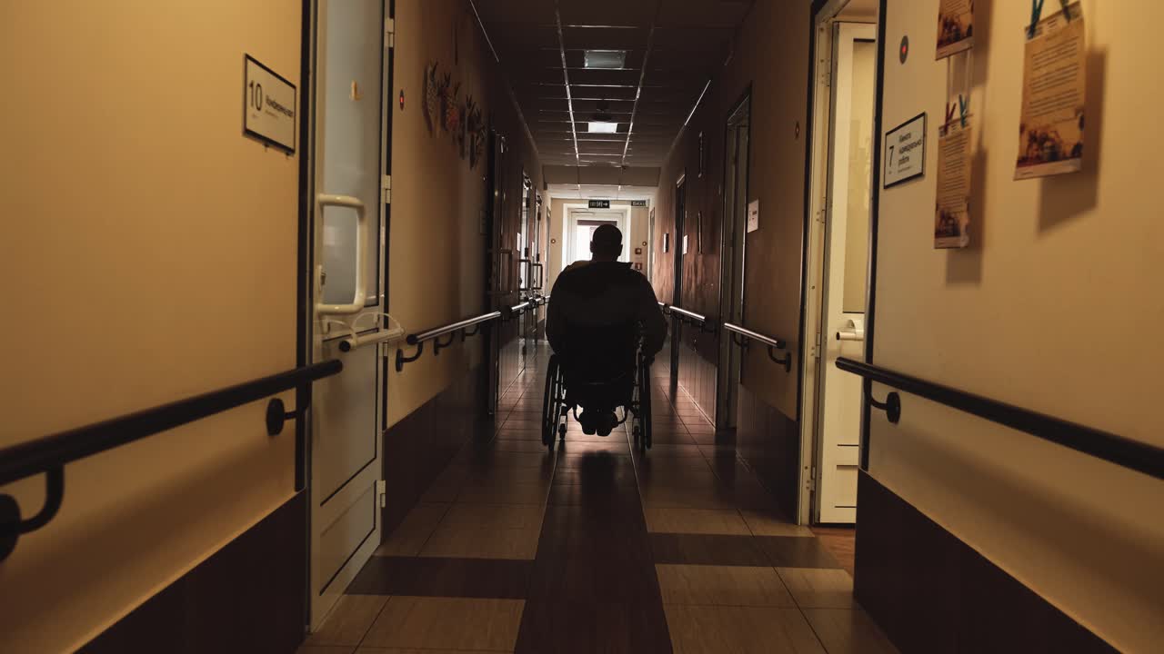 hombre con discapacidad en silla de ruedas caminando por un largo pasillo