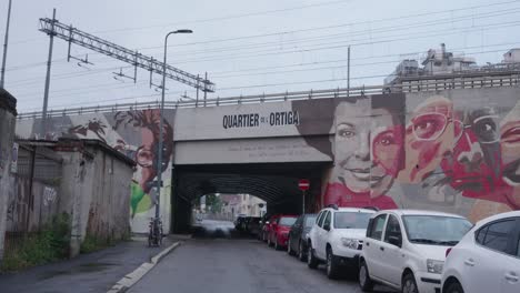 Cars-parked-under-railway-bridge-in-suburbs-of-Milan,-handheld-view