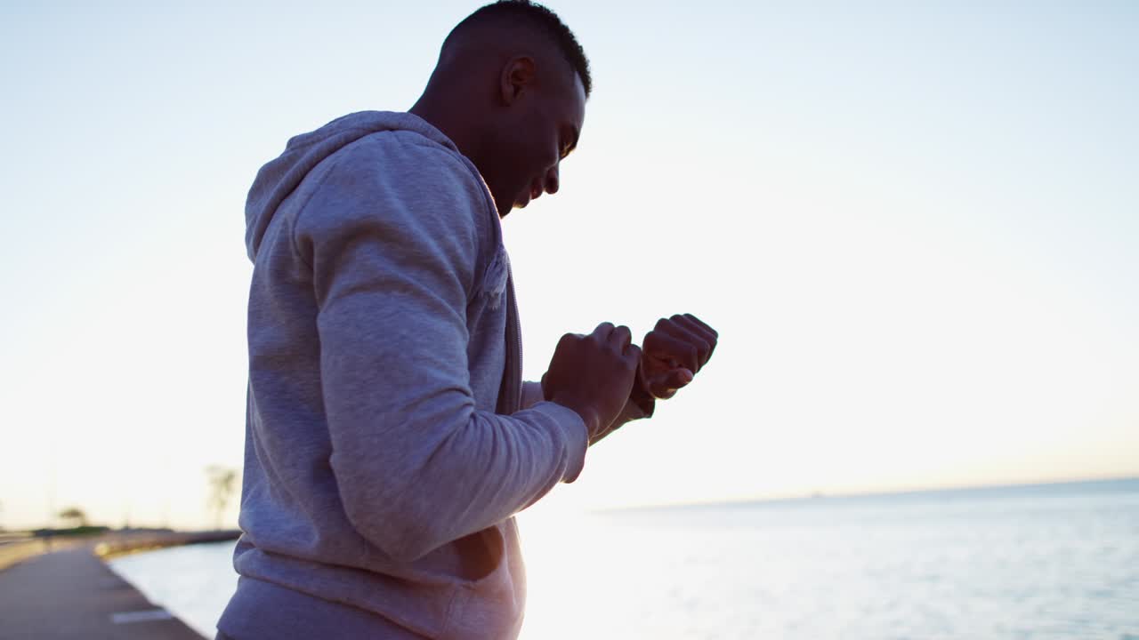 hombre étnico en la llamarada solar usando un monitor de cardio