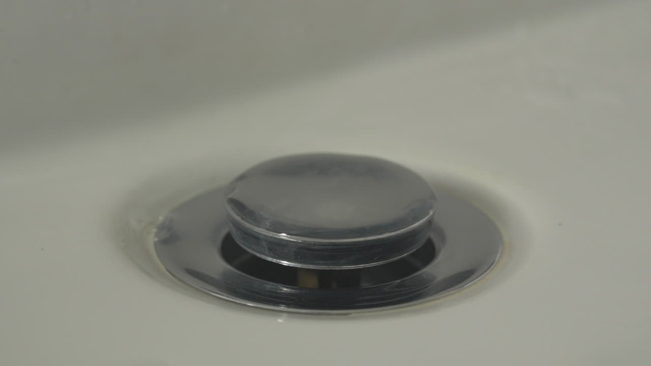 Water droplets falling quickly into the basin of the sink