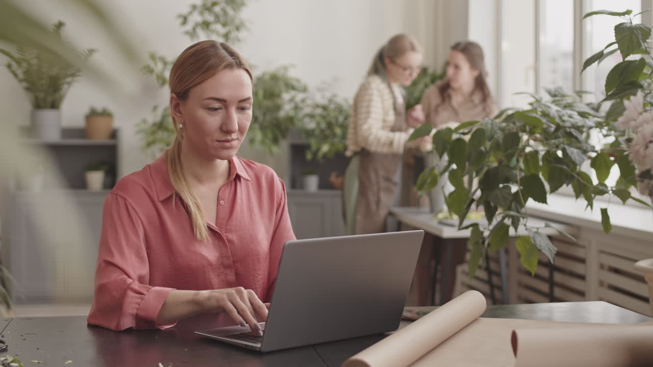 Donna che lavora al laptop in un negozio di fiori