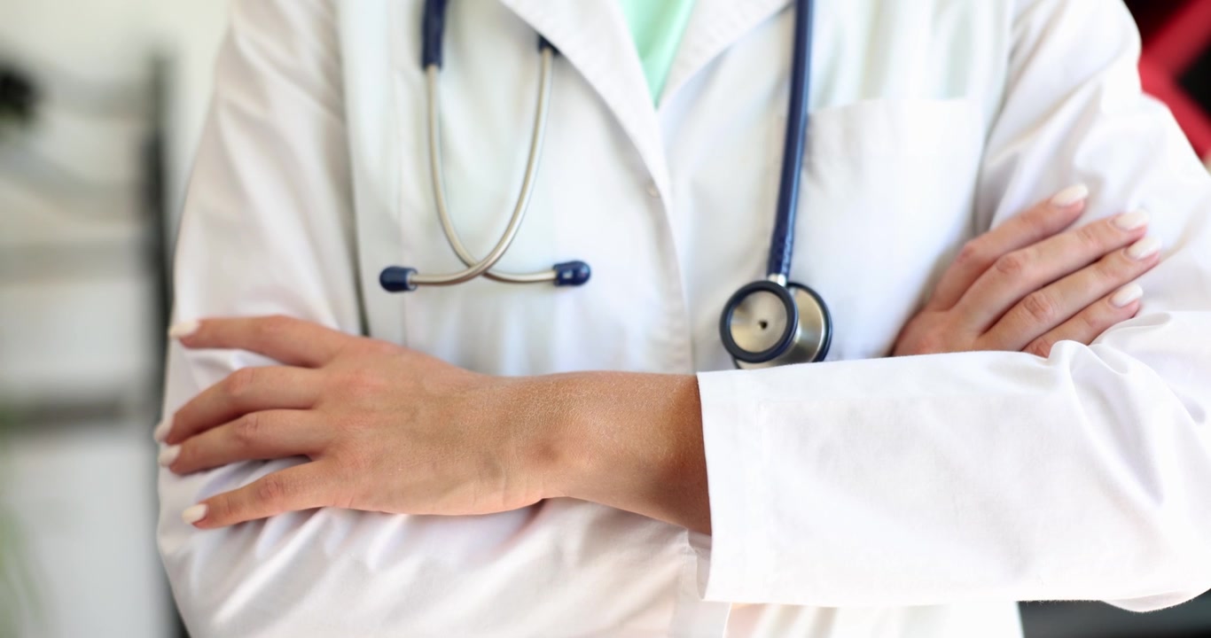 Medico in uniforme sta in piedi con sicurezza con le braccia incrociate.