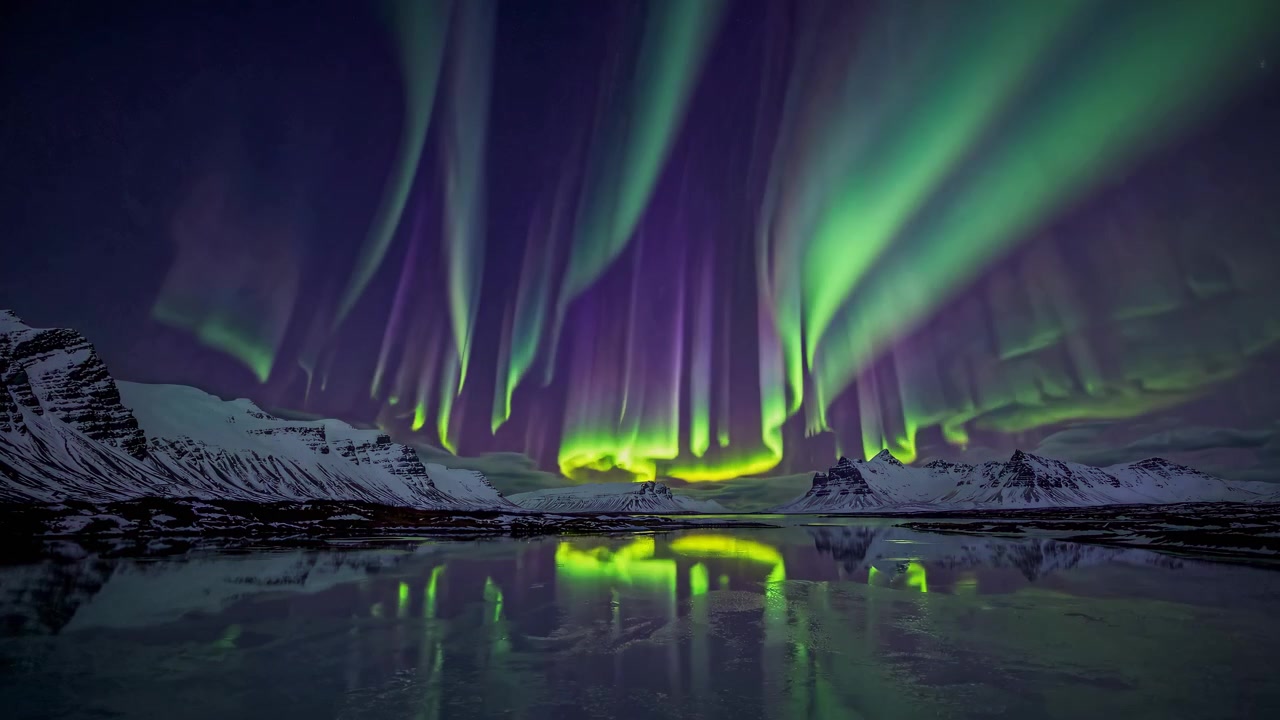 Vivace aurora boreale che danza sopra montagne innevate e un lago ghiacciato