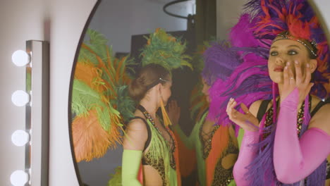 hermosa mujer en vestido colorido usando maquillaje mientras su equipo la espera