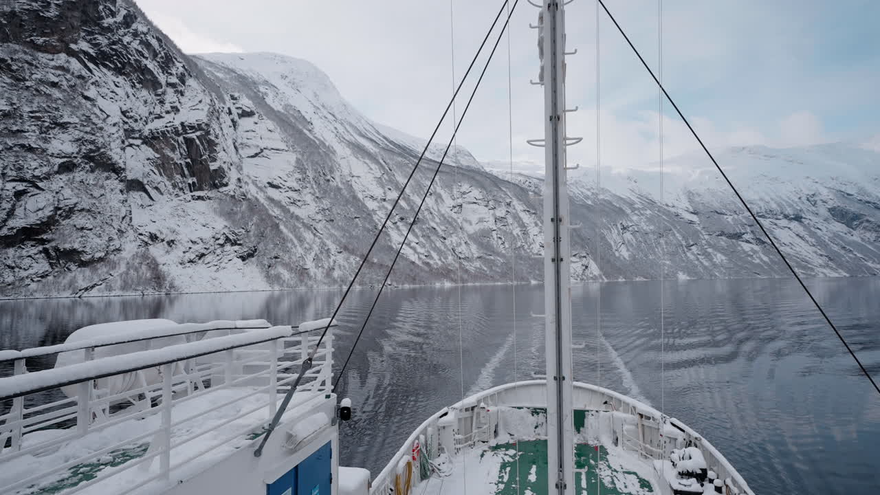 노르웨이의 geirangerfjord에서 눈 인 산과 매혹적인 피오르드 전망을 가진 겨울 페리 보트 타기의 느린 동작