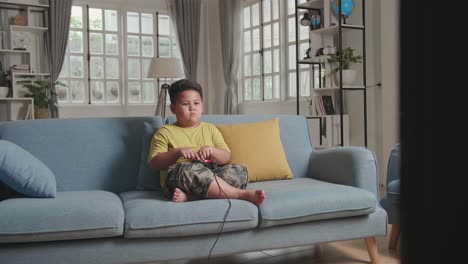 young boy using his fingers playing game at home, sitting on a couch
