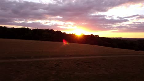 Moving-towards-a-stunning-sunset-sky-aerial-shot-over-fields-in-Hitchin,-Hertfordshire,-England,-Uk