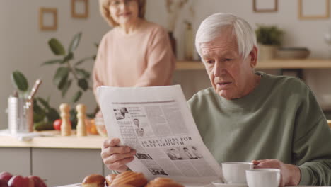 portrait of senior man with newspaper and coffee at home