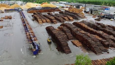 aerial view of activity at sawmill yard with stacked logs being sprayed wet