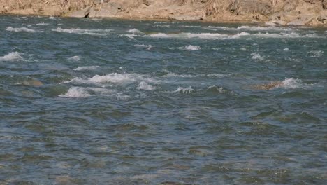 stone skipping on water. throwing a small flattened rock bouncing off water surface across body of water many times and finally sinking in the lake, river, sea or ocean