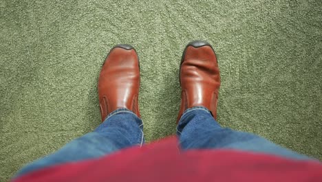 person standing on carpet wearing brown shoes and jeans