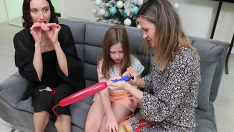 family and friends making balloon animals together at home during the holidays