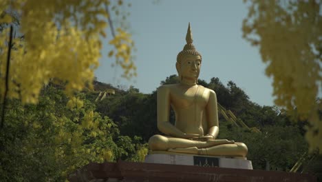 a golden seated buddha surrounded by yellow flowers