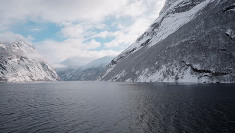 slow motion pov of a winter ferry boat ride in geirangerfjord to geiranger, norway, with snowy mountains and captivating fjord views