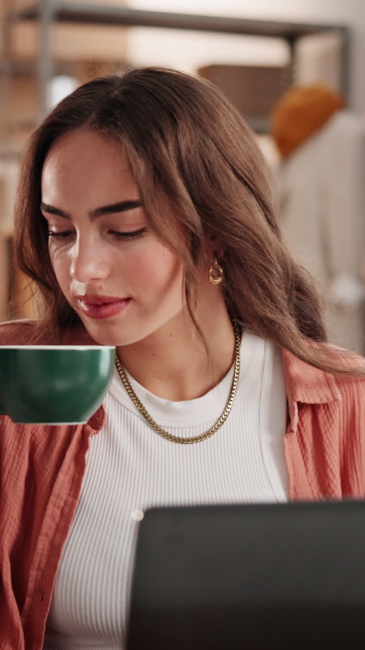 Giovane donna che sorseggia un caffè mentre lavora al portatile