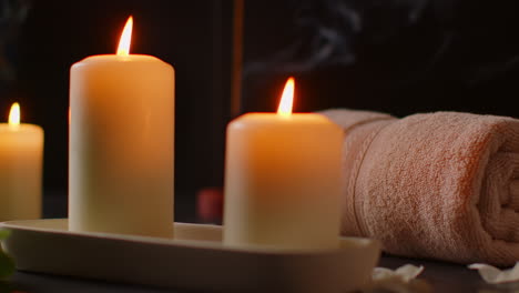 vida muerta de velas encendidas con pétalos esparcidos palillo de incienso y toallas suaves contra un fondo oscuro como parte de la relajante decoración del día de spa 2