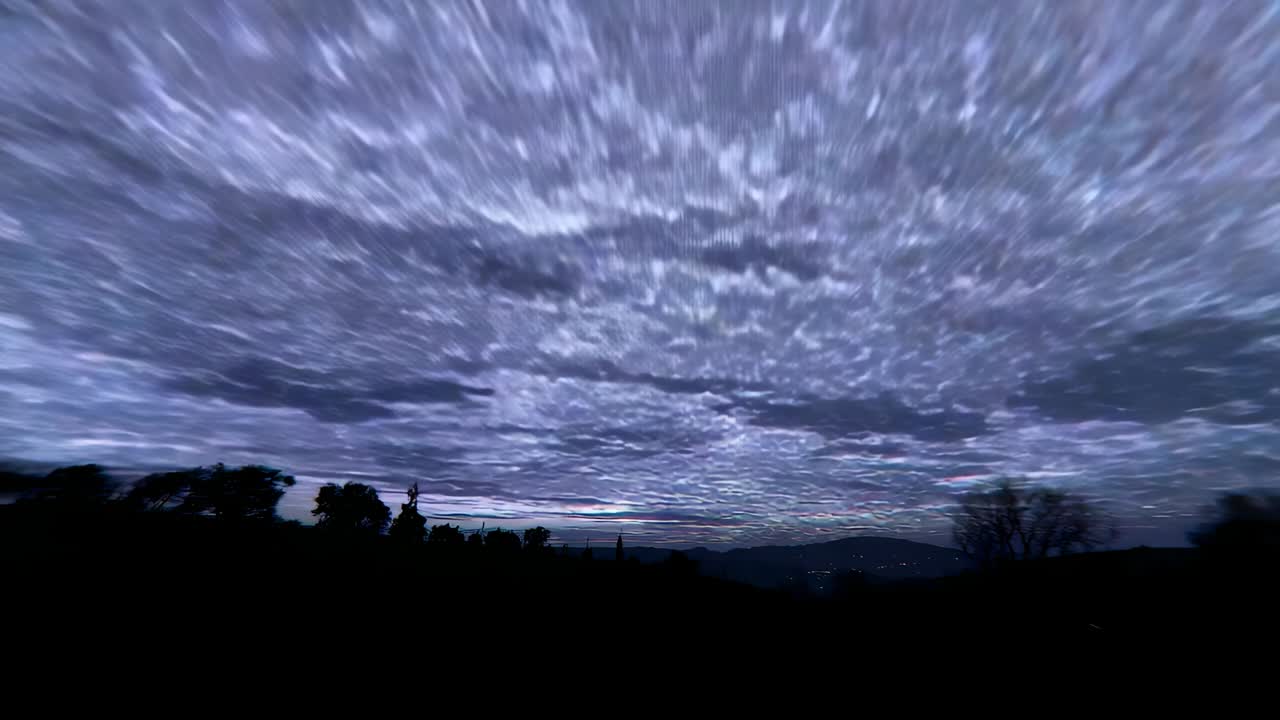 Starting timelapse showing nighttime cloud layer drifting over rural hillside, with town lights