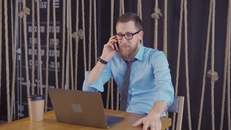 hombre de negocios en el teléfono en la oficina con una computadora portátil