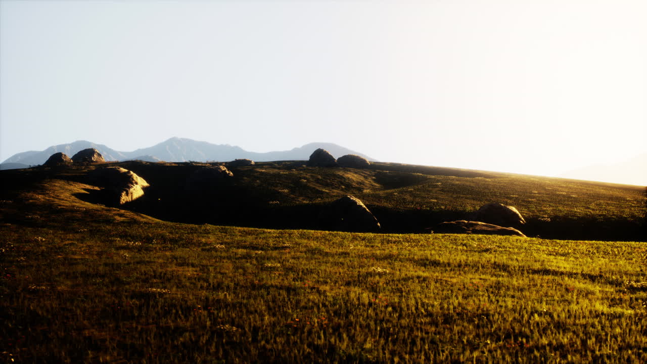 배경 에 산 들 이 있는 잔디 들 위 에 해 가 지는 것