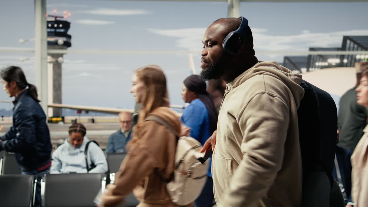 Walking, audio headphones and man in busy airport hallway