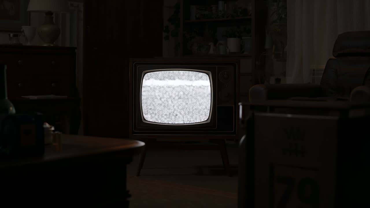 Accensione di un televisore CRT vintage in legno che mostra rumore statico in un soggiorno scarsamente illuminato, con tavolino da caffè