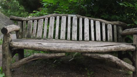 Flower-pollen-gently-drifts-down,-mimicking-a-snowfall,-in-front-of-a-rustic-park-bench-crafted-from-spare-logs,-providing-a-serene-visual