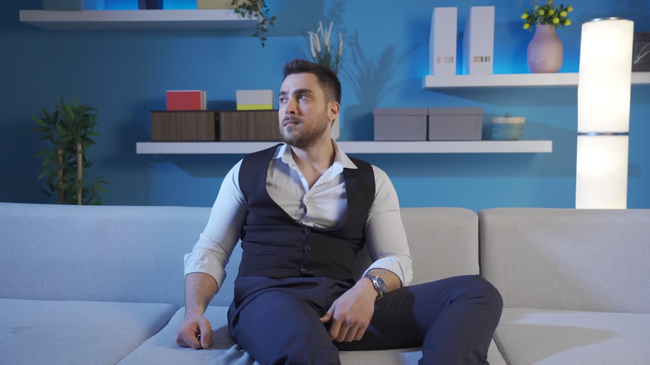 거실에 앉아 있는 남자는 주위를 둘러보기를 갈망하고 있습니다.