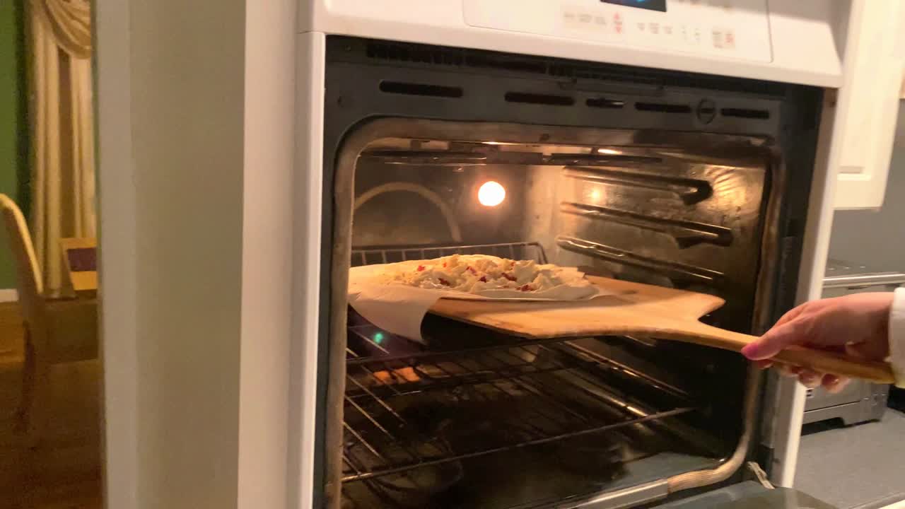 Metiendo una pizza blanca con tocino en el horno.