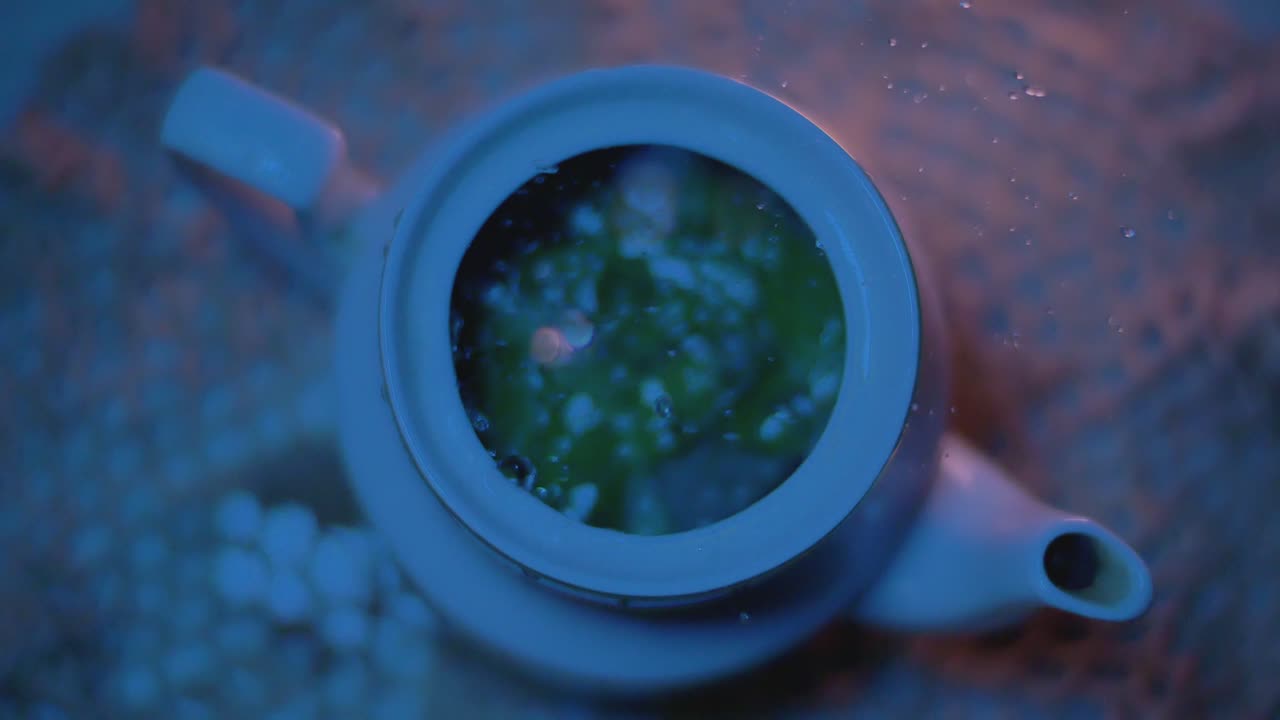 el agua se vierte descuidadamente desde arriba en una tetera en la oscuridad