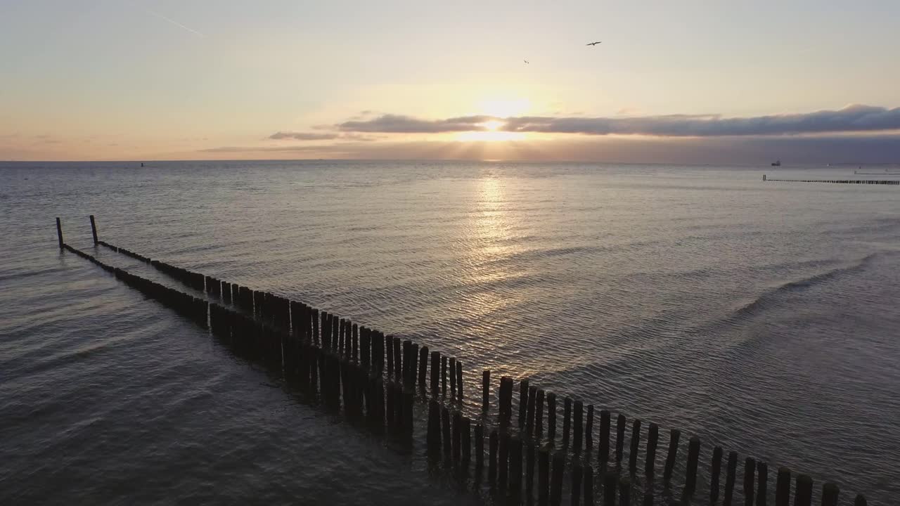 Tramonto sul mare con pali di legno