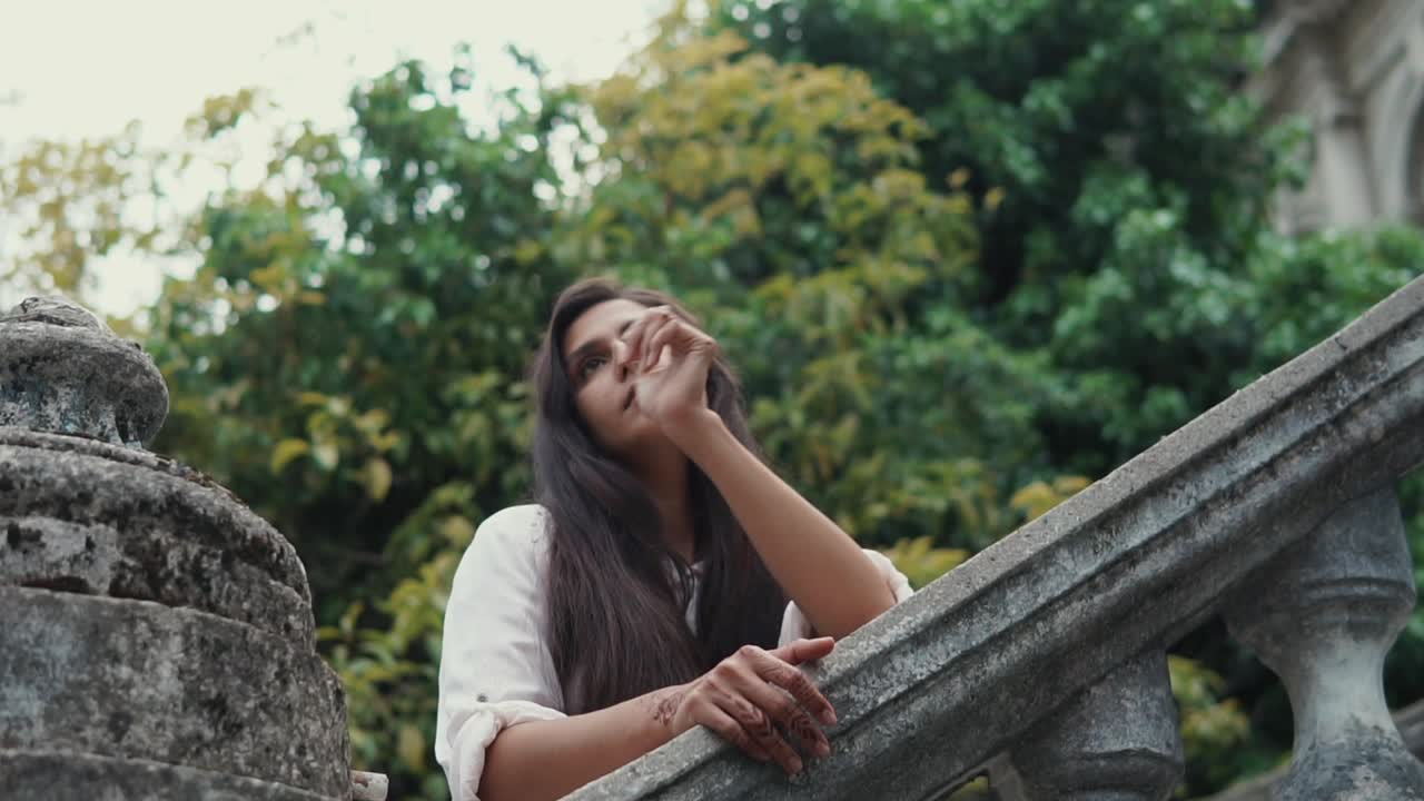 mujer apoyada en viejas escaleras de piedra en un jardín